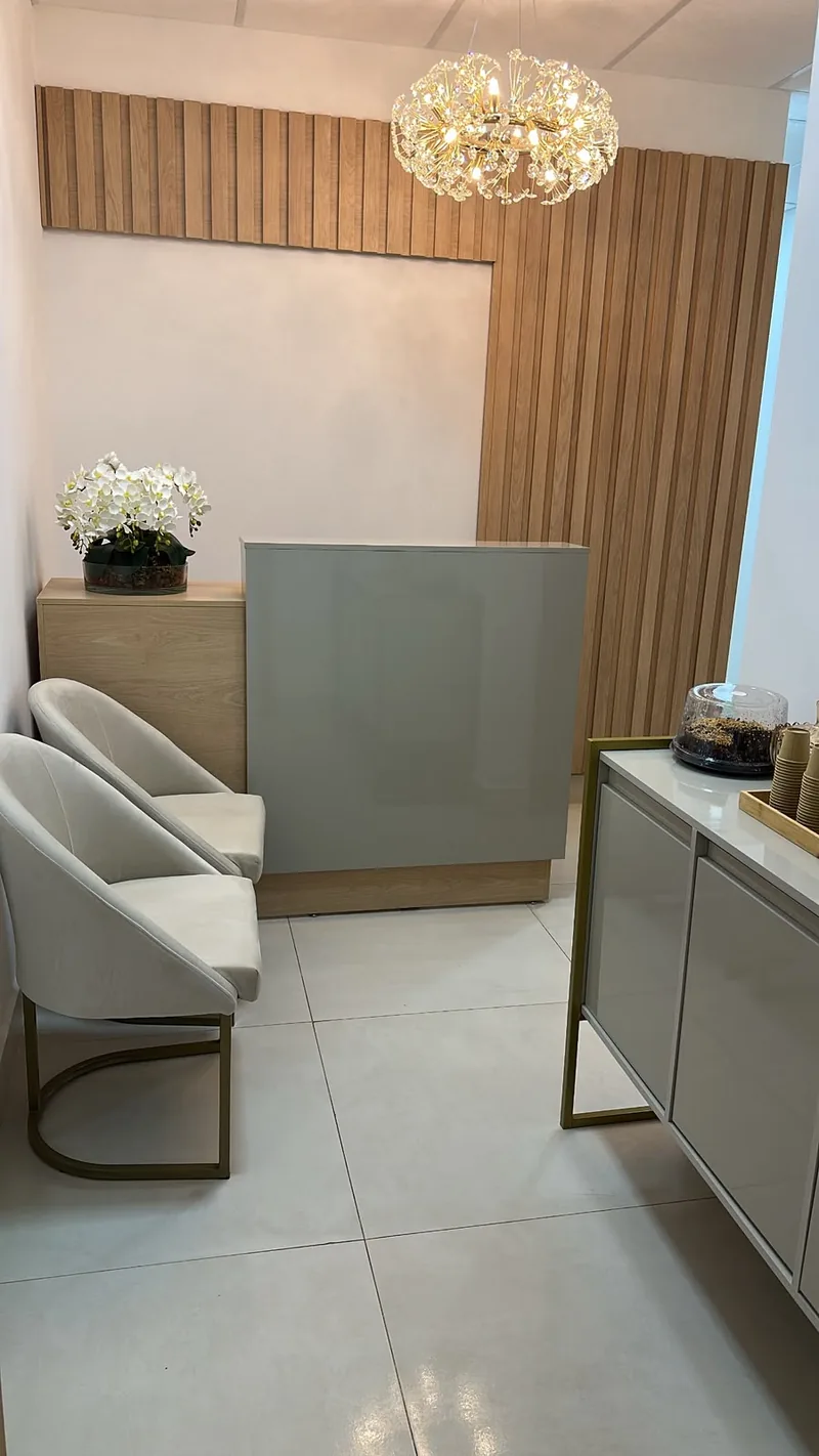 Recepção do consultório com balcão, poltronas e lustre